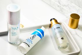 Bottles of hyaluronic acid serums on vanity tray on white marble countertop
