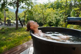 A young woman taking an ice bath or cold plunge in a cabin in the woods
