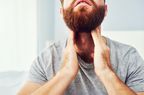 A man touches his throat with both hands
