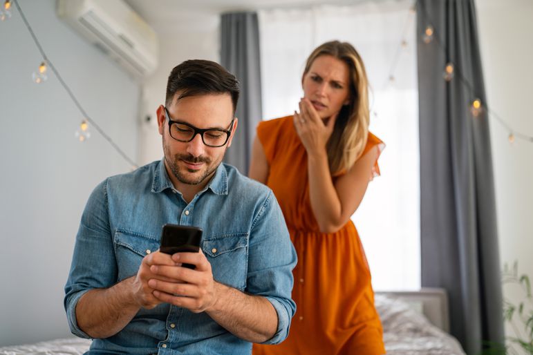A jealous woman spying on her boyfriend and watching him text on his mobile phone