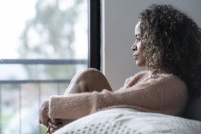 Woman sitting at home looking out the window