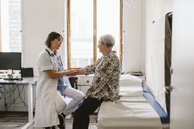 doctor examining older female patient in hospital 