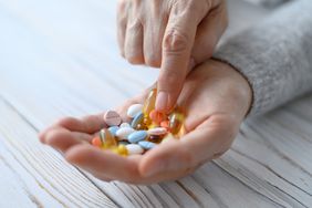 A bunch of pills in the hands of an elderly woman