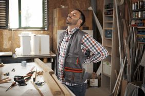 person with middle back pain while working
