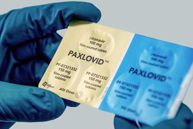 Person wearing gloves holding Paxlovid medication