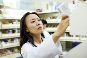 Close-up of female pharmacist arranging drugs on rack