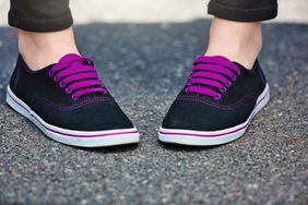 Close-up pigeon-toed feet with black shoes and purple laces