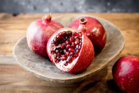 A close-up shot of pomegranates on a wooden bowl