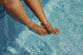Close up of a person's legs while they dip their feet in the pool.