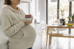 An older pregnant woman drinking a hot drink