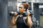 A fit, young African American woman working out with hand weights in a fitness gym.