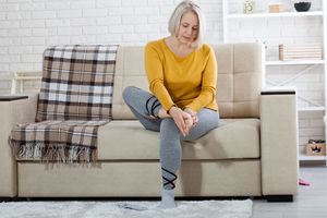 Older woman examining her feet for joint symptoms. 