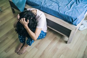 woman with psychosis keeping her head down and sitting on the floor