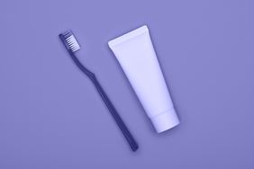 A close up of a toothbrush and toothpaste on purple background
