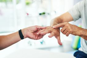 doctor checking pustular psoriasis on person's hand