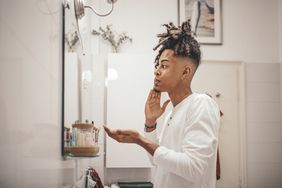 man in front of mirror applying skincare product