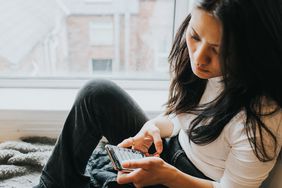 An elevated view of a concerned looking woman looking down at her mobile phone device