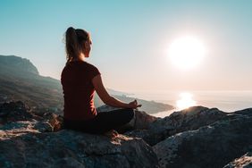 A woman meditating at sunrise
