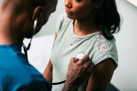 doctor using stethoscope on woman