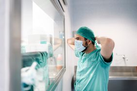 Unrecognizable doctor covering his face with mask in hospital.