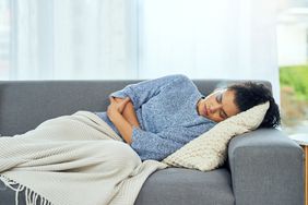 person with stomach flu sick on cough with stomach pain