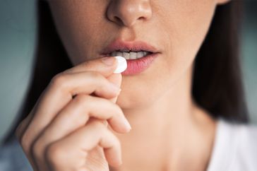 Close up cropped image unhealthy young woman taking round pill