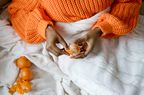 Woman Hands Peeling Ripe Sweet Tangerine Wearing Orange Sweater Lying In Bed Under The Blanket