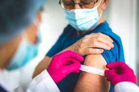 Doctor giving first aid bandage after vaccination to senior woman