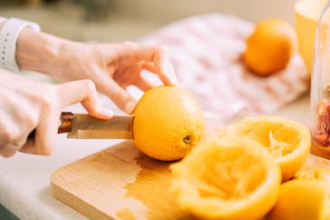 Close-up of a woman slicing oranges with vitamin c